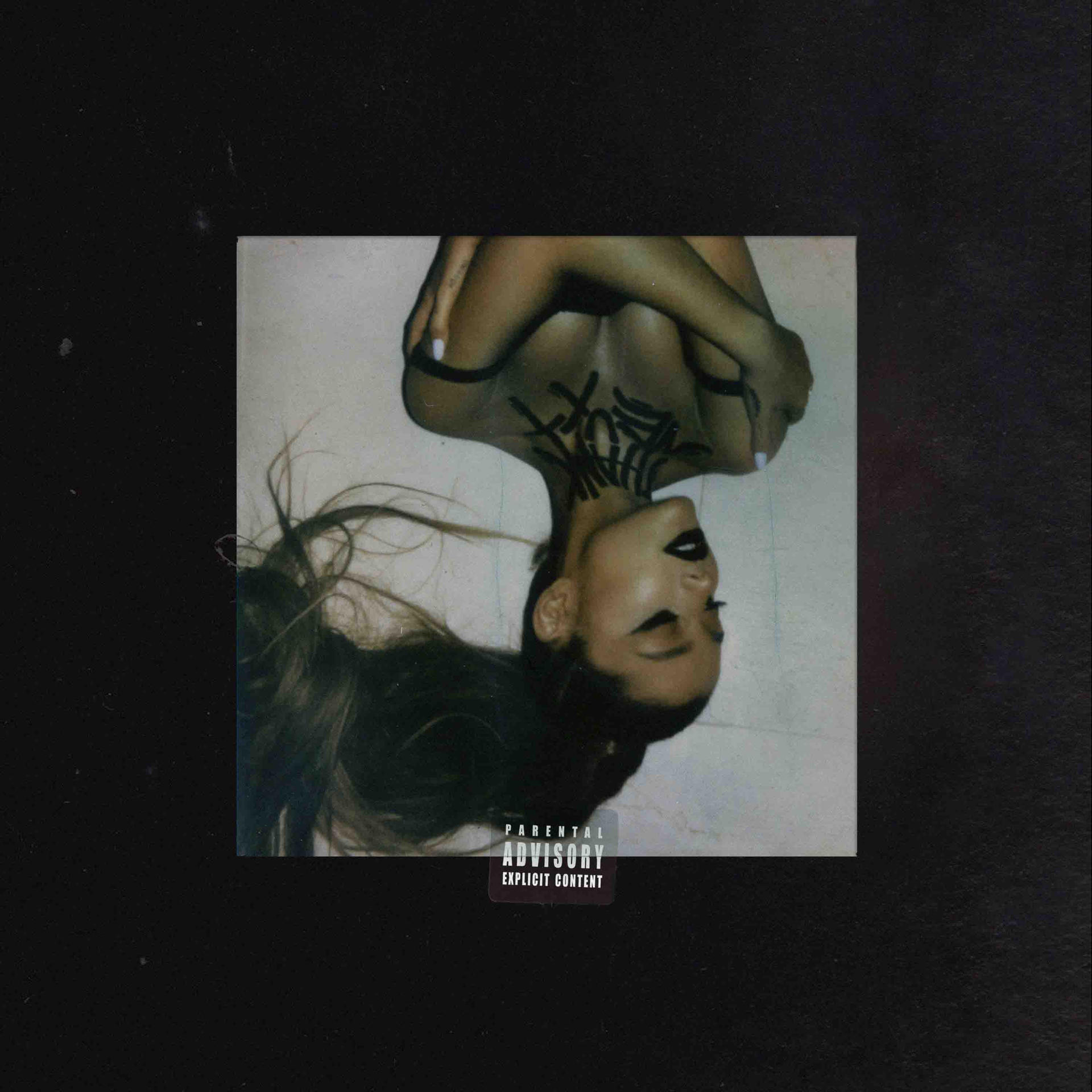 Pochette d'album d'Ariana Grande. Image à l'envers d'elle avec des tatouages sur le cou. Fond noir.