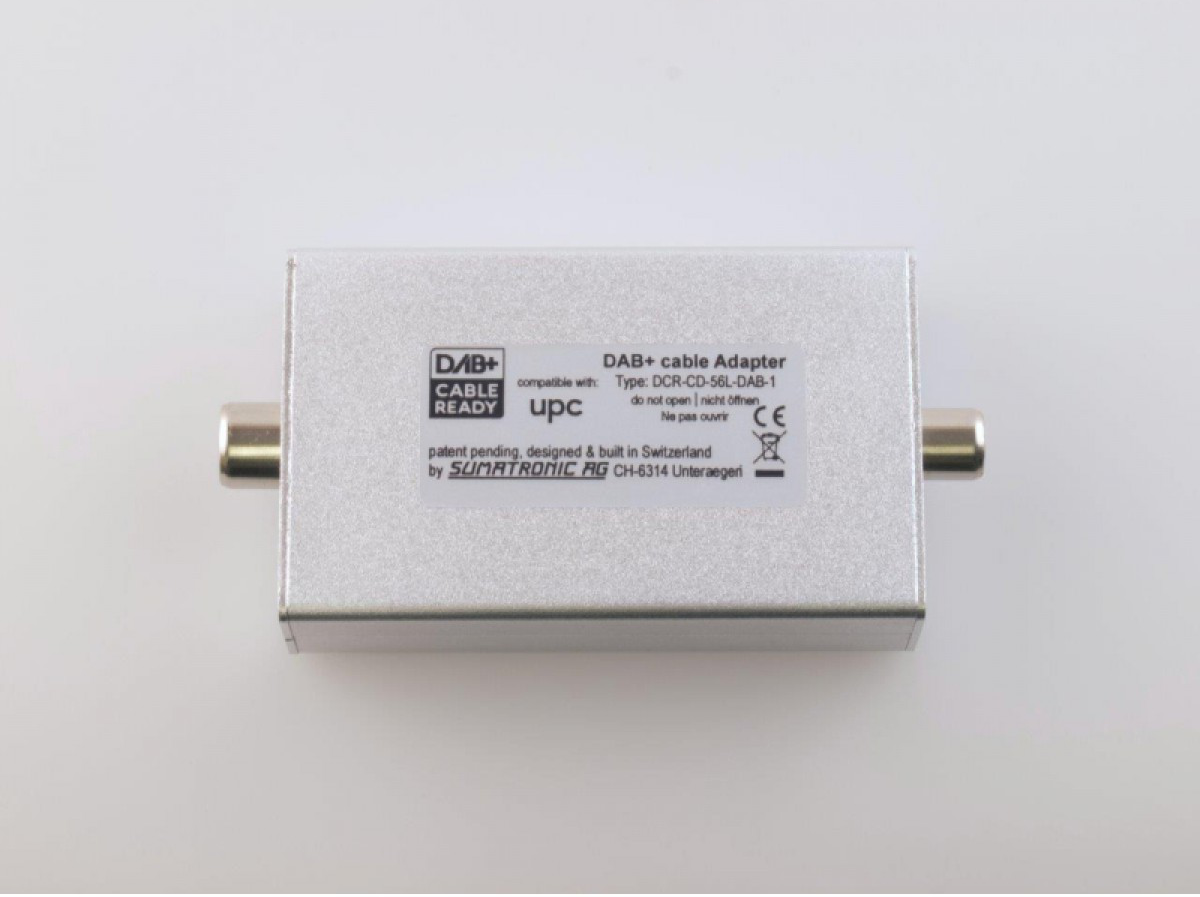 Adaptateur de câble DAB+ argenté avec connecteurs à chaque extrémité et texte sur le dessus.