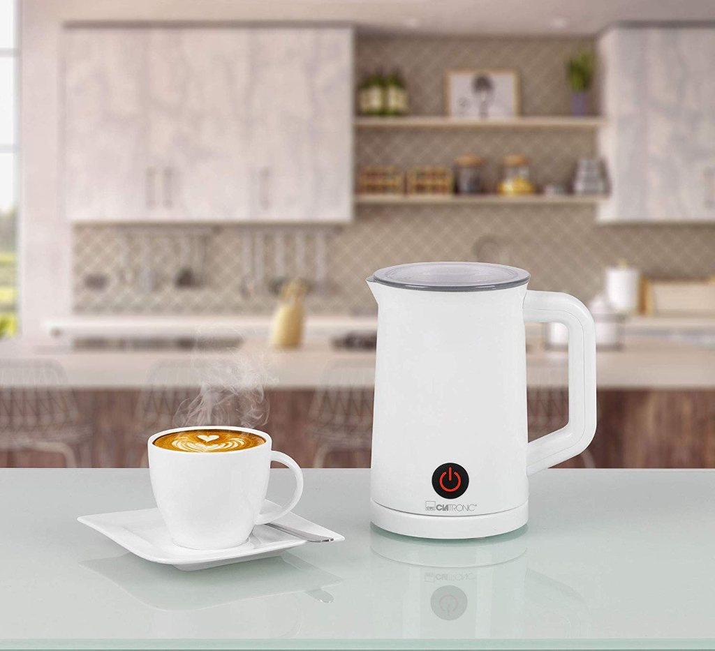 Fehér elektromos tejhabosító egy csésze kávé mellett, latte art-tal.
