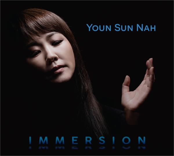 Eine Frau, die nach oben schaut, mit erhobener Hand und dem Wort IMMERSION unten, mit dem Namen.