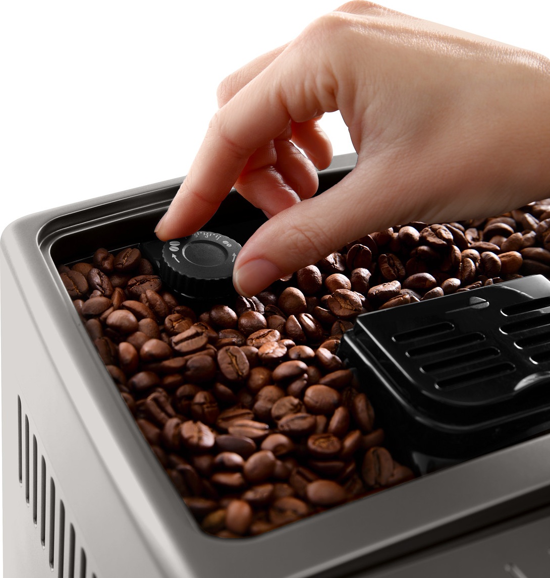 Hand, die einen schwarzen Drehregler an einem Kaffeebohnenbehälter einstellt. Der Behälter ist mit Kaffeebohnen gefüllt.