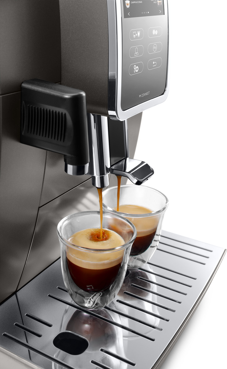 Eine Kaffeemaschine, die Espresso in zwei klare Glasbecher gießt, auf einem Metalltablett.