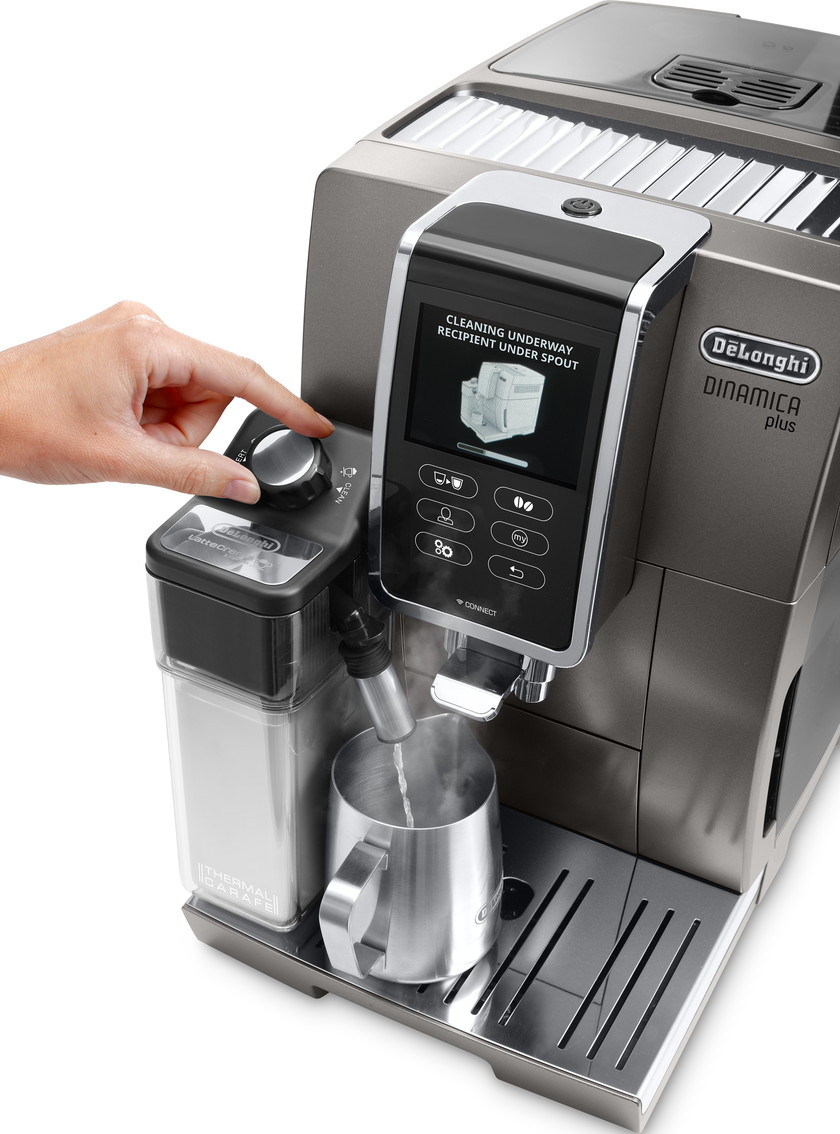 Kaffeemaschine mit Hand, die einen Drehregler einstellt. Dampf in eine Metalltasse.