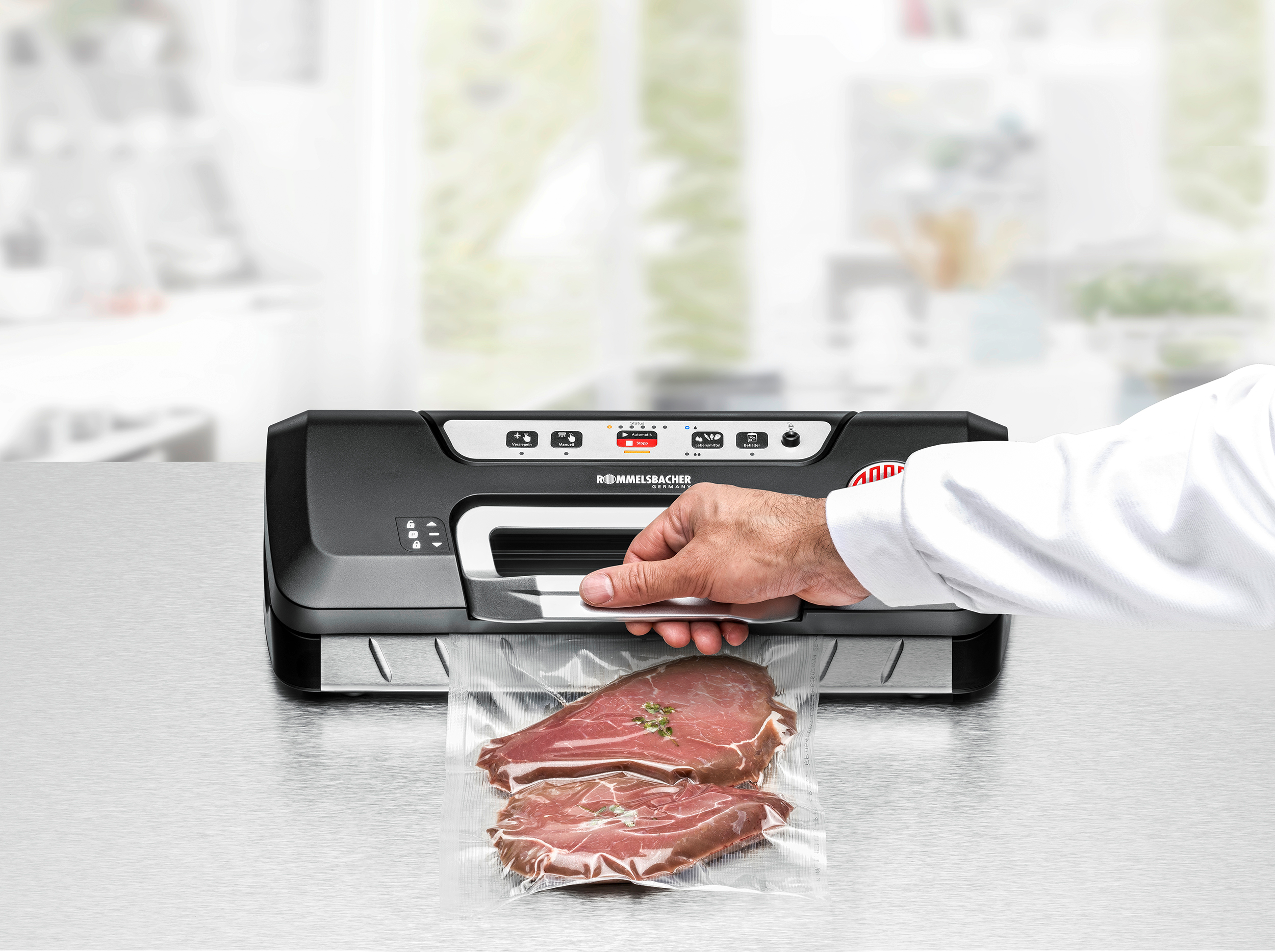 Eine Person versiegelt eine Tüte Fleisch mit einem schwarzen Vakuumierer auf einer Metalloberfläche.