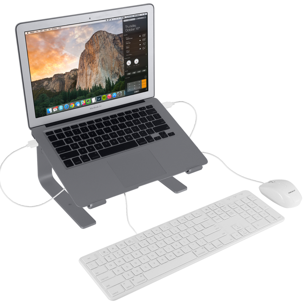 Ordinateur portable sur un support argenté, avec clavier et souris. Câbles connectés. Fond blanc.