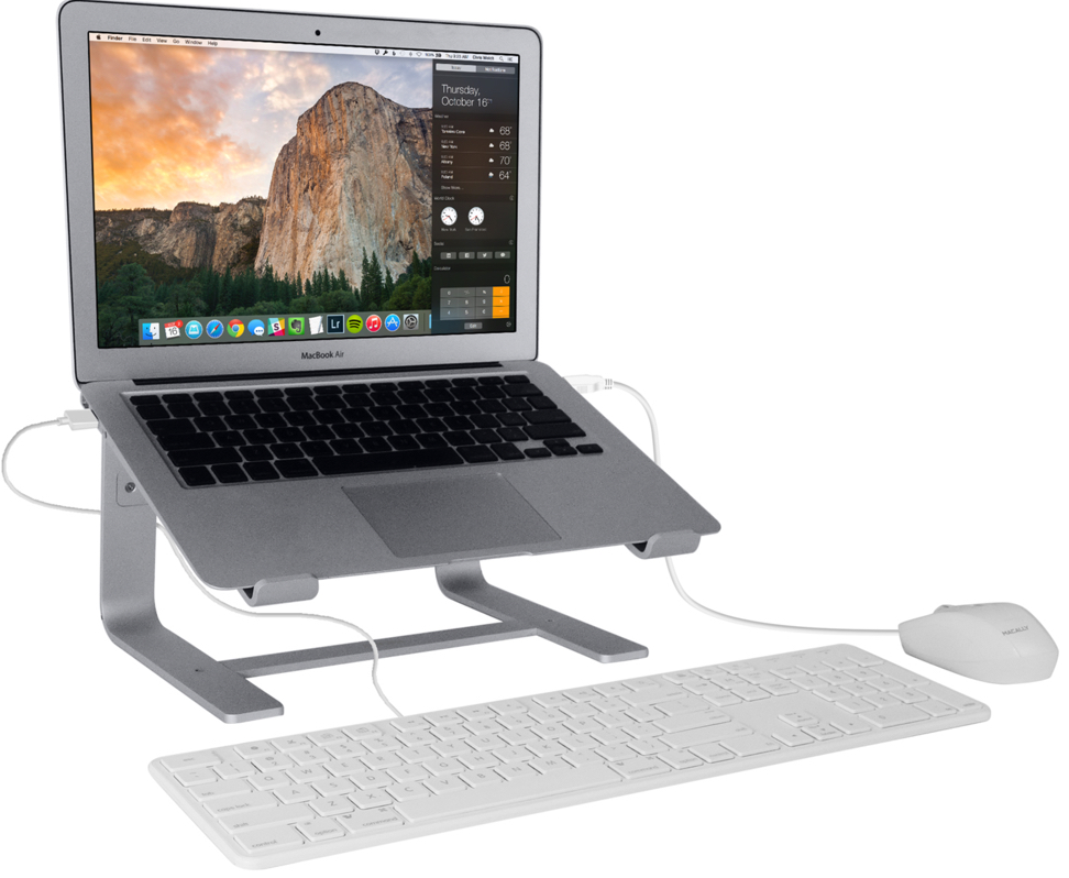 Ordinateur portable argenté sur un support argenté avec un clavier et une souris. Un arrière-plan de montagne.