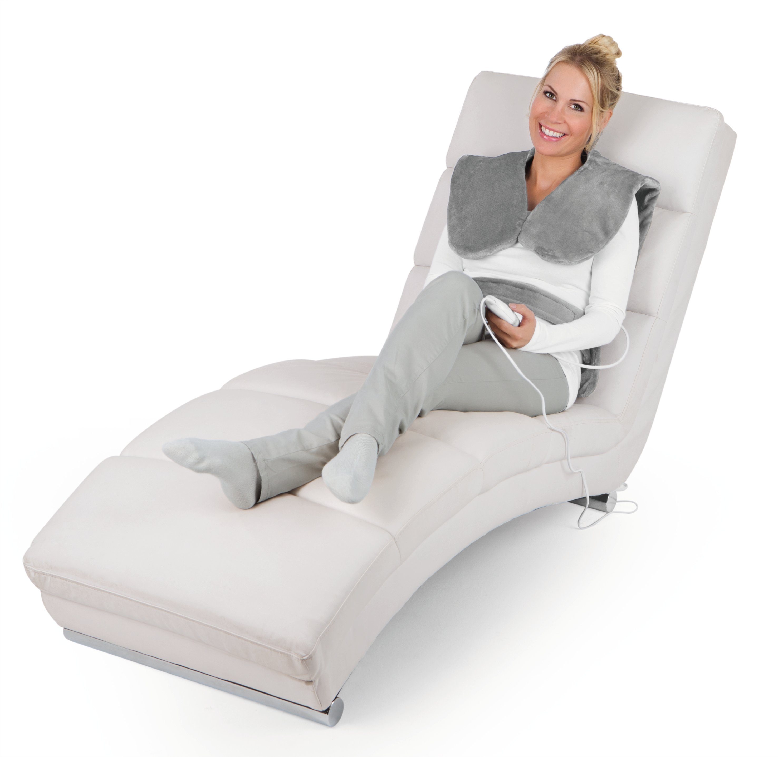Frau mit grauem Heizkissen auf weißer Chaiselongue, lächelnd.