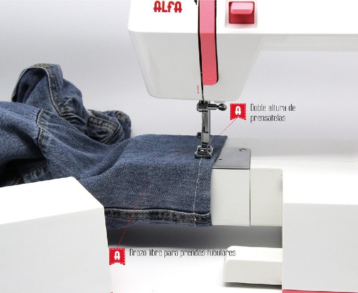Una máquina de coser cose tela vaquera azul con etiquetas y texto rojos.