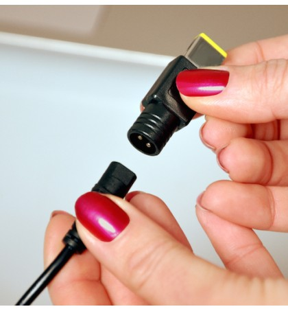 Mani che tengono un cavo di alimentazione per laptop nero e giallo, pronto per il collegamento.
