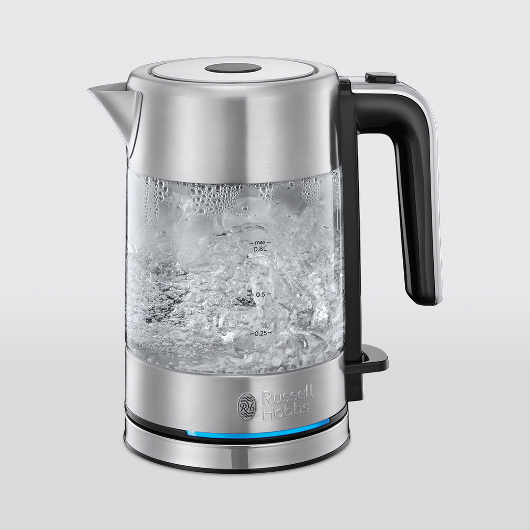 Ein elektrischer Wasserkocher aus Klarglas und Edelstahl, mit kochendem Wasser und blauem Licht.