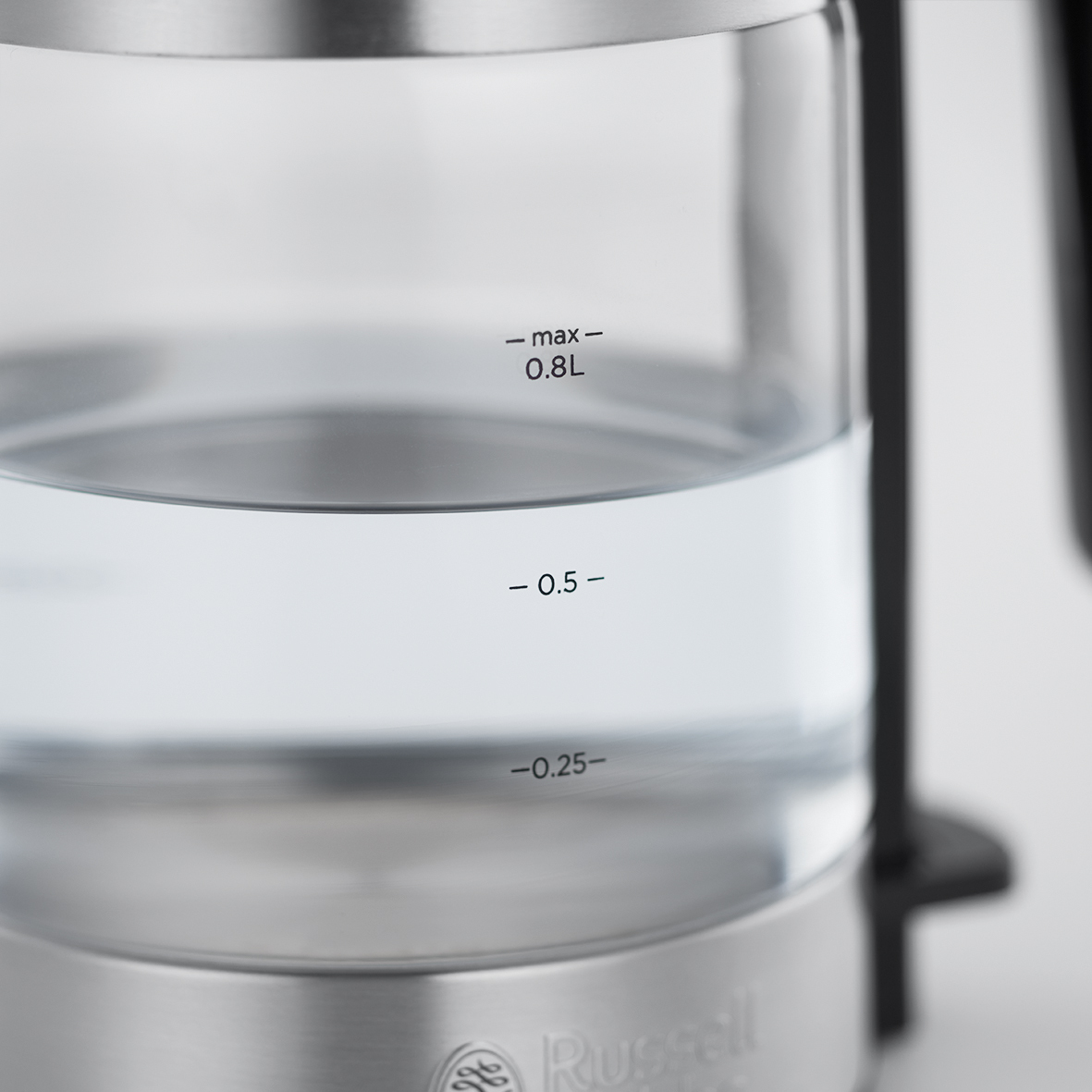 Glaskessel mit Wasser. Wasserstandmarkierungen sind sichtbar, mit schwarzem Griff.