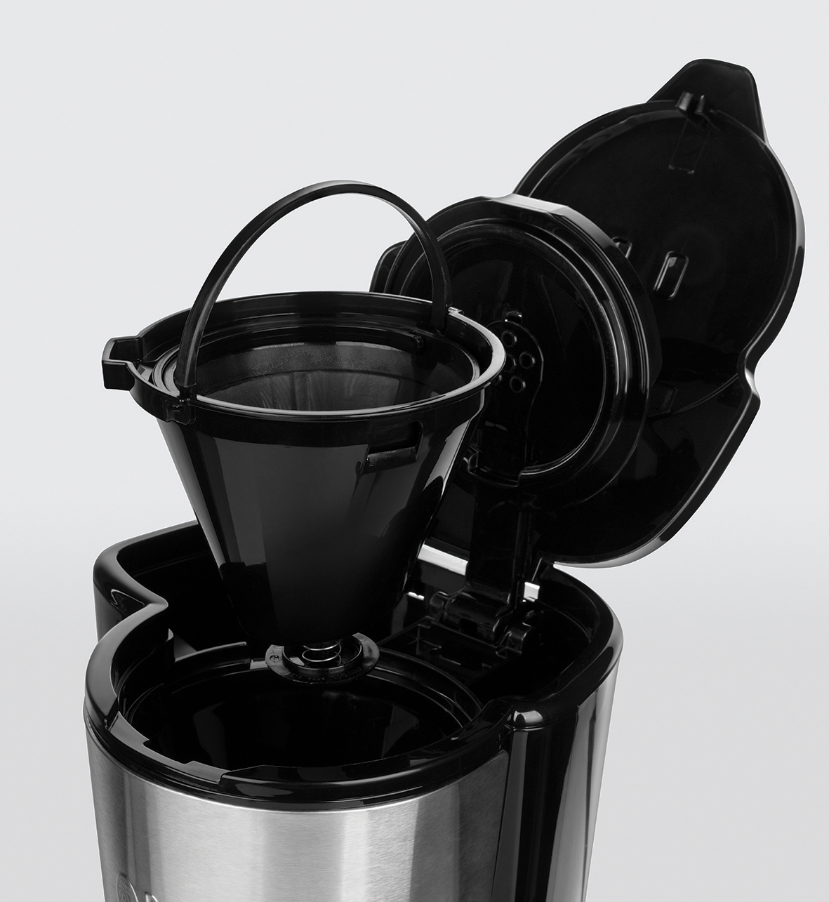 Das Innere einer Kaffeemaschine. Der Filter ist offen, und es gibt einen schwarzen Filter. Weißer Hintergrund.