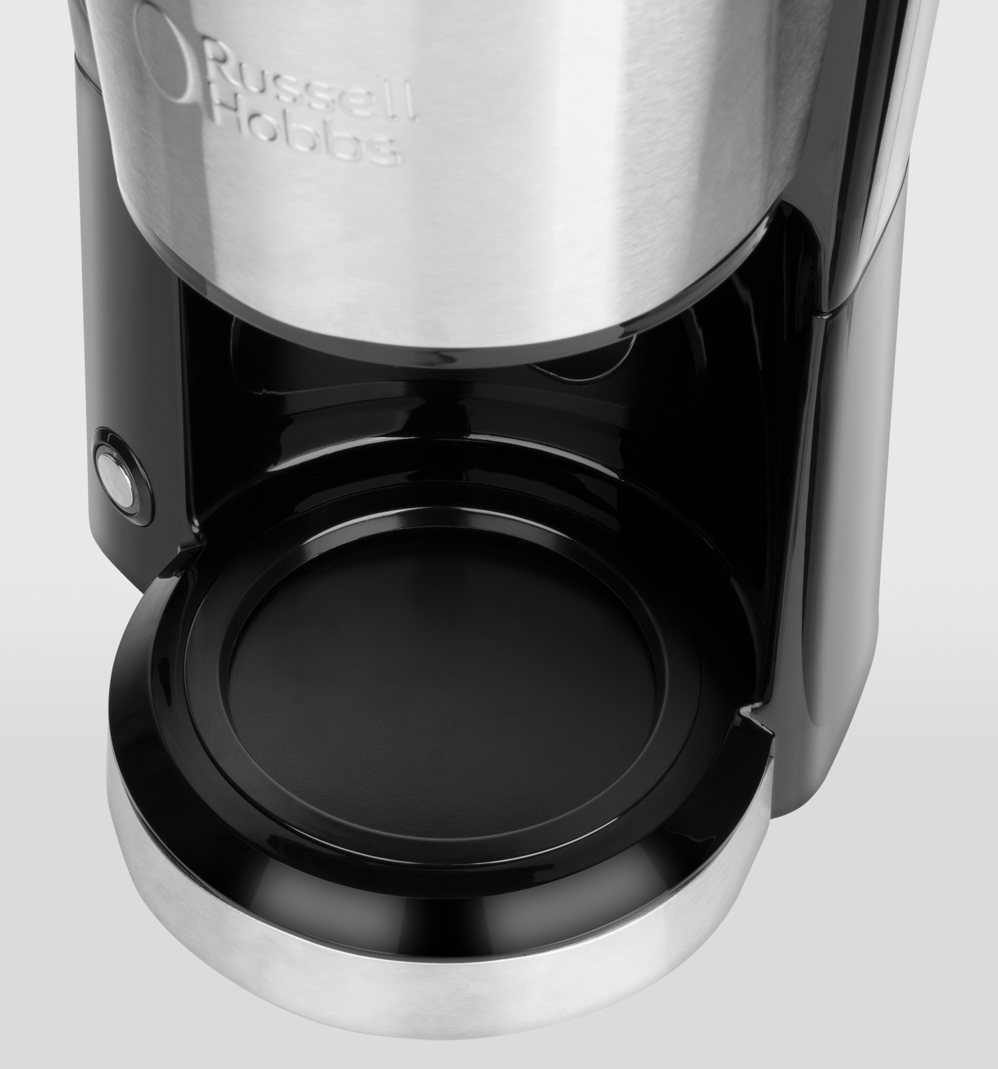 Der untere Teil einer Kaffeemaschine. Es ist schwarz und silber. Weißer Hintergrund.