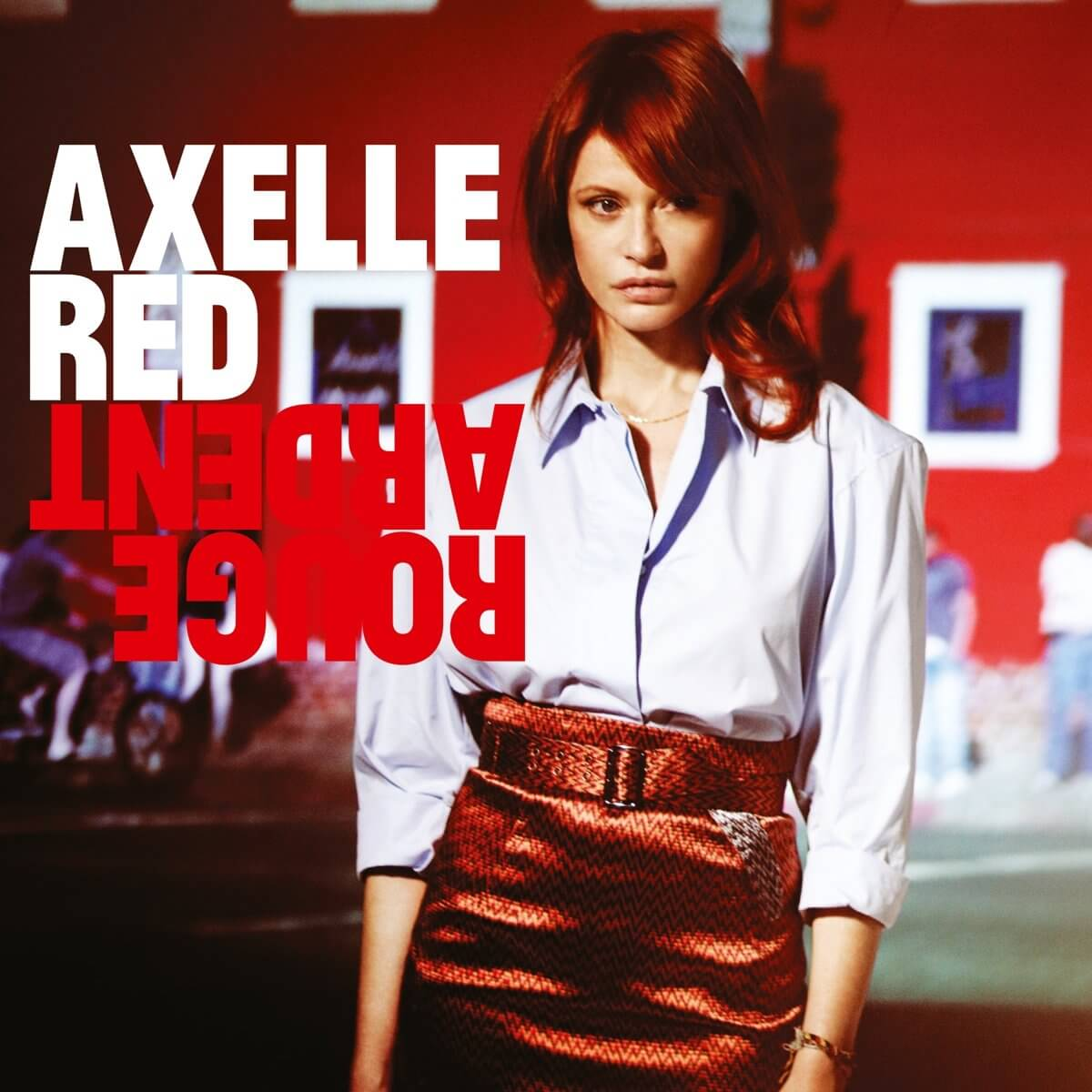 Couverture de l'album Axelle Red. Une femme en chemise blanche et jupe rouge devant un bâtiment rouge.