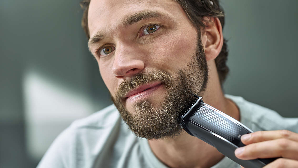 Homme utilisant une tondeuse à barbe. Gros plan de son visage, taillant sa barbe.