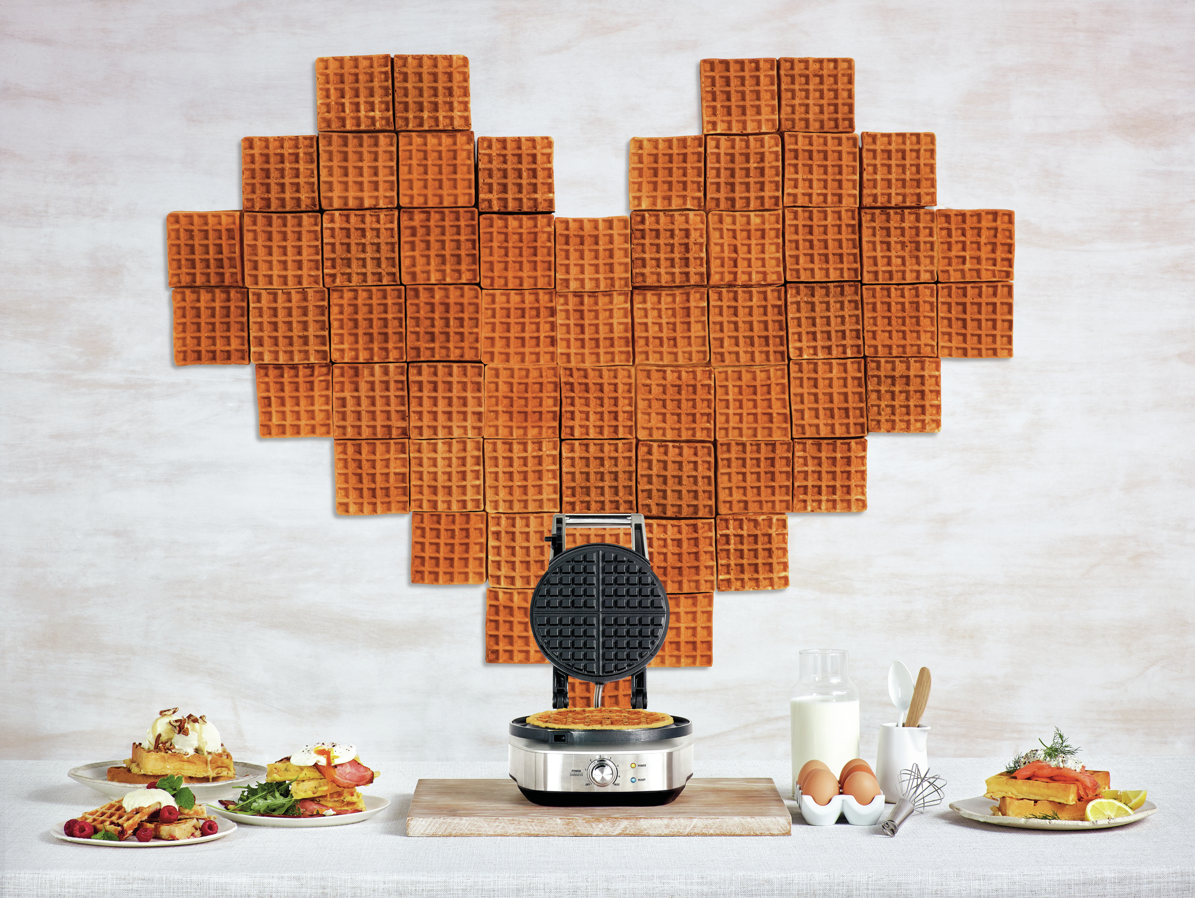Waffeln in Herzform, Waffeleisen. Gerichte mit Essen an den Seiten.
