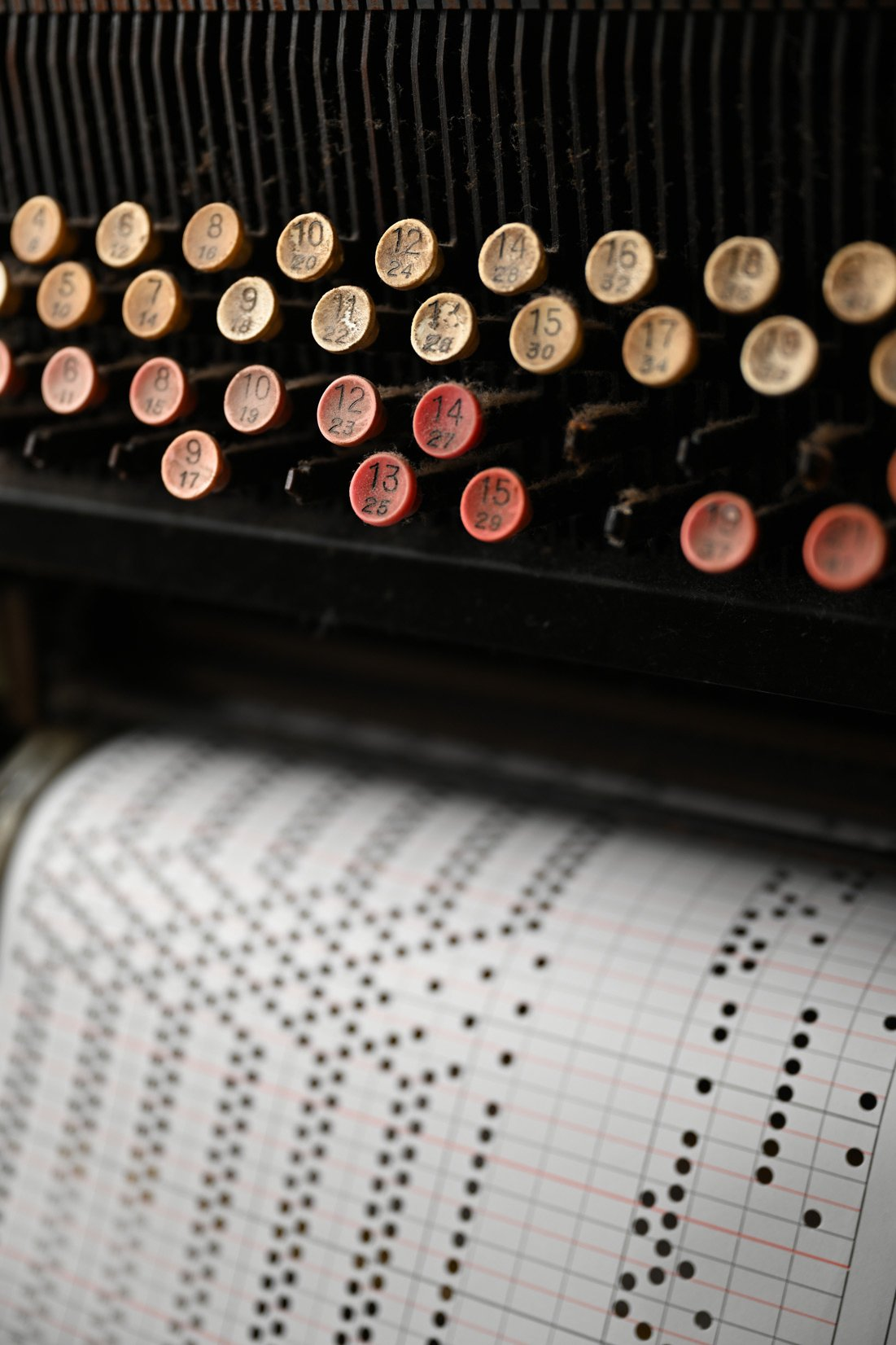 Gros plan d'une machine à écrire antique. Touches avec chiffres et lettres visibles. Un rouleau de papier devant.