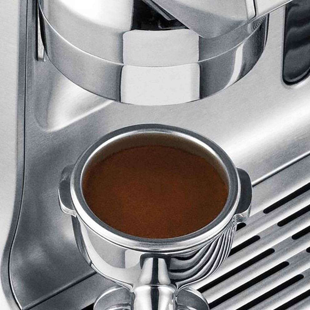 Nahaufnahme eines Espresso-Shots in einem Siebträger einer silbernen Espressomaschine.
