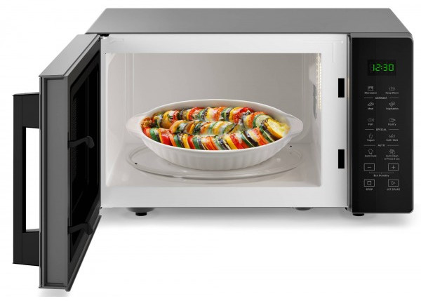 Un four à micro-ondes avec la porte ouverte. À l'intérieur, un plat de légumes cuits.