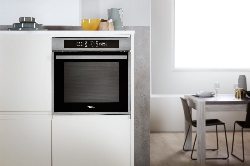 Horno empotrado en una cocina blanca. La pantalla digital muestra la hora y la temperatura. El horno es negro.