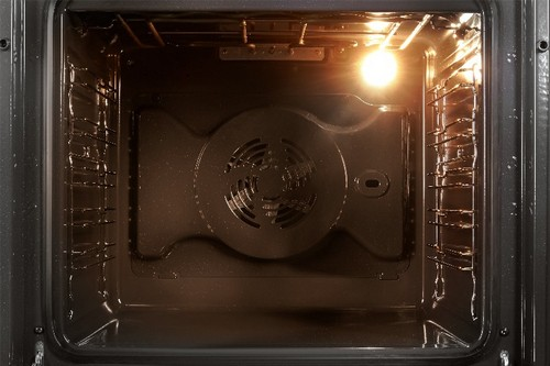 Interior de un horno, con elementos calefactores y luz visibles.