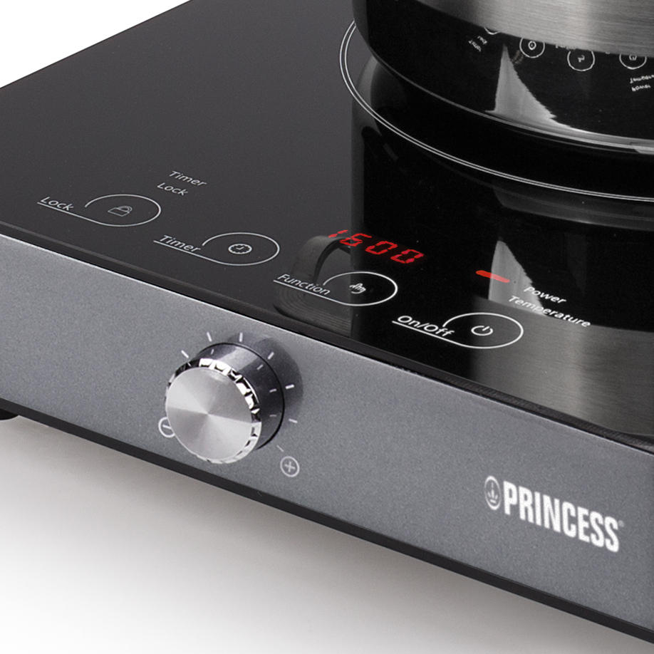 Close-up van een inductiekookplaat. Display toont 16:00. Princess logo. Zilveren draaiknop.