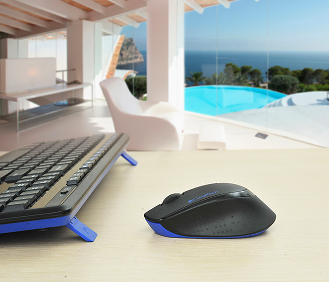 Desk with a keyboard, mouse, and a blurred view of a pool and a house.