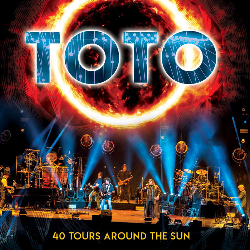 A TOTO együttes album borítója, nap grafikával és élő színpadi előadással.