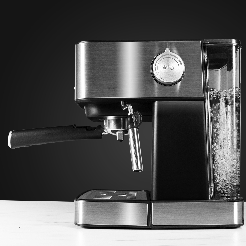 Primer plano de una máquina de espresso plateada y negra con un depósito de agua. Burbujas suben en el depósito de agua transparente. La máquina está sobre una superficie blanca.