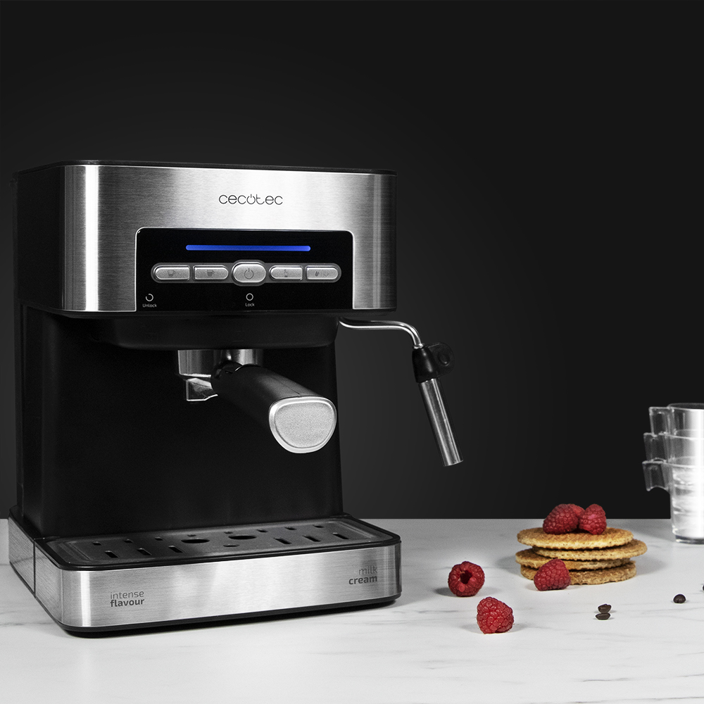 Cafetera espresso con frambuesas y gofres sobre superficie de mármol. Fondo negro.