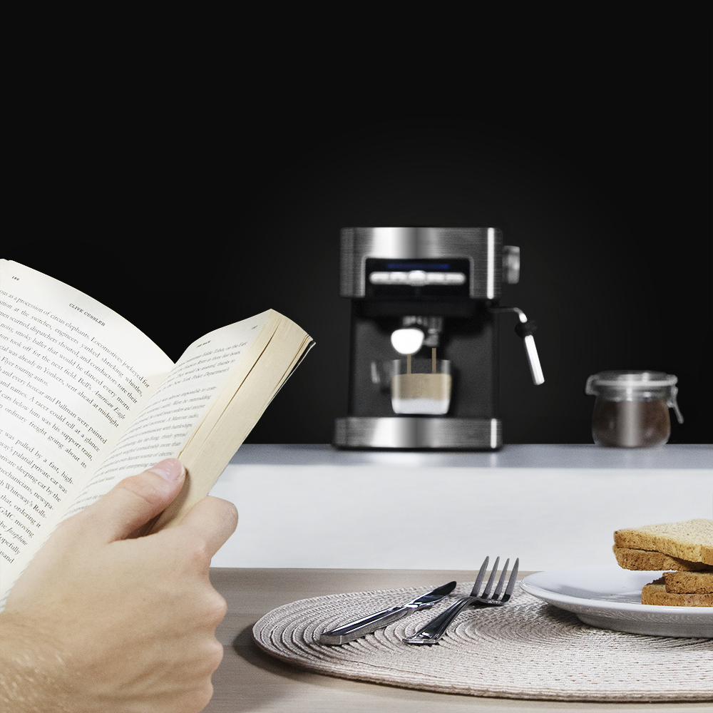 Una persona lee un libro con café y tostadas en la mesa. Una cafetera está en el fondo.