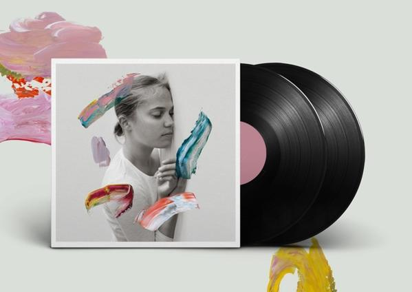Albumcover mit einer Frau und Farbe. Zwei Schallplatten liegen neben dem Cover. Weißer Hintergrund.