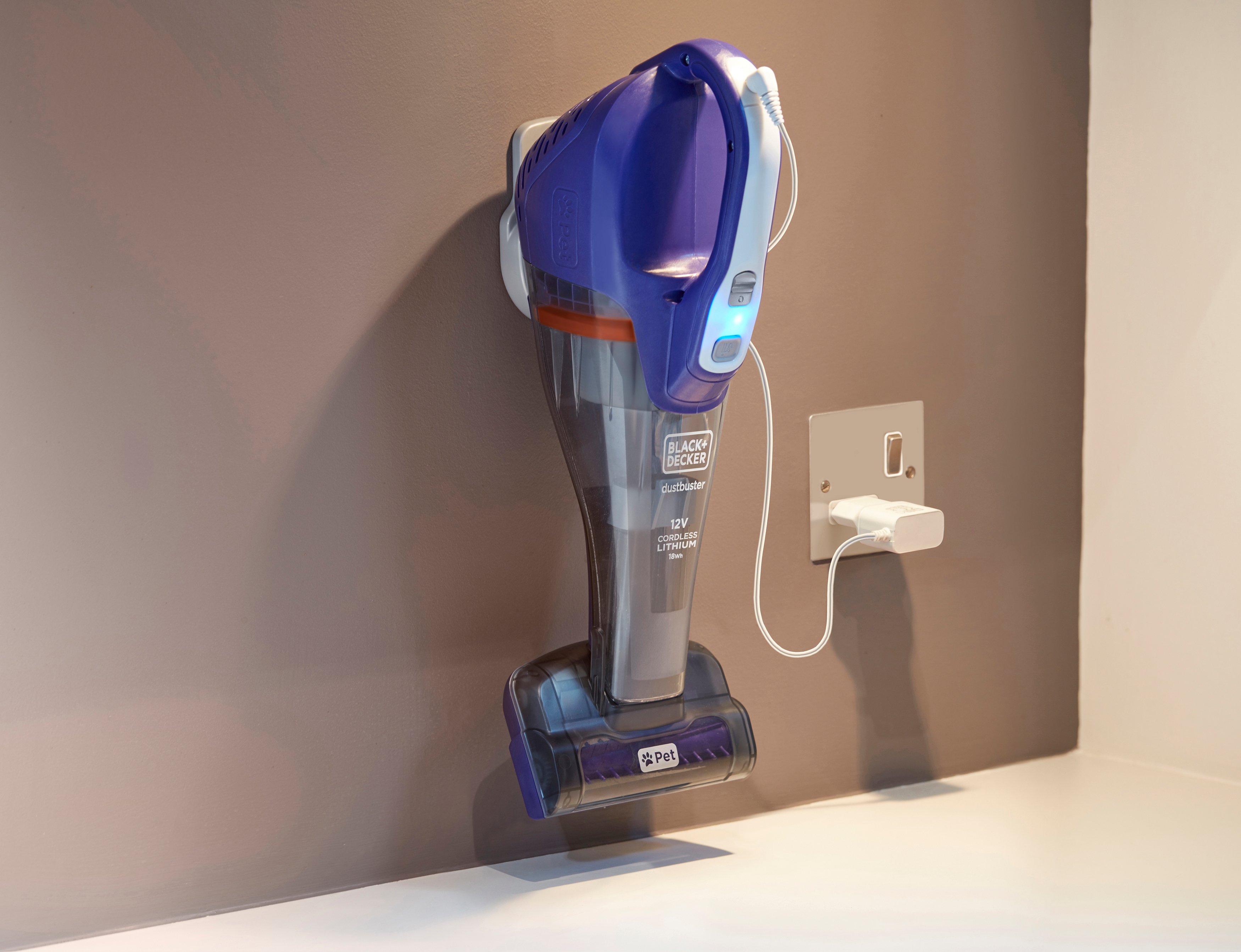 Ein kabelloser Black+Decker Staubsauger, der an einer Wandhalterung geladen wird.