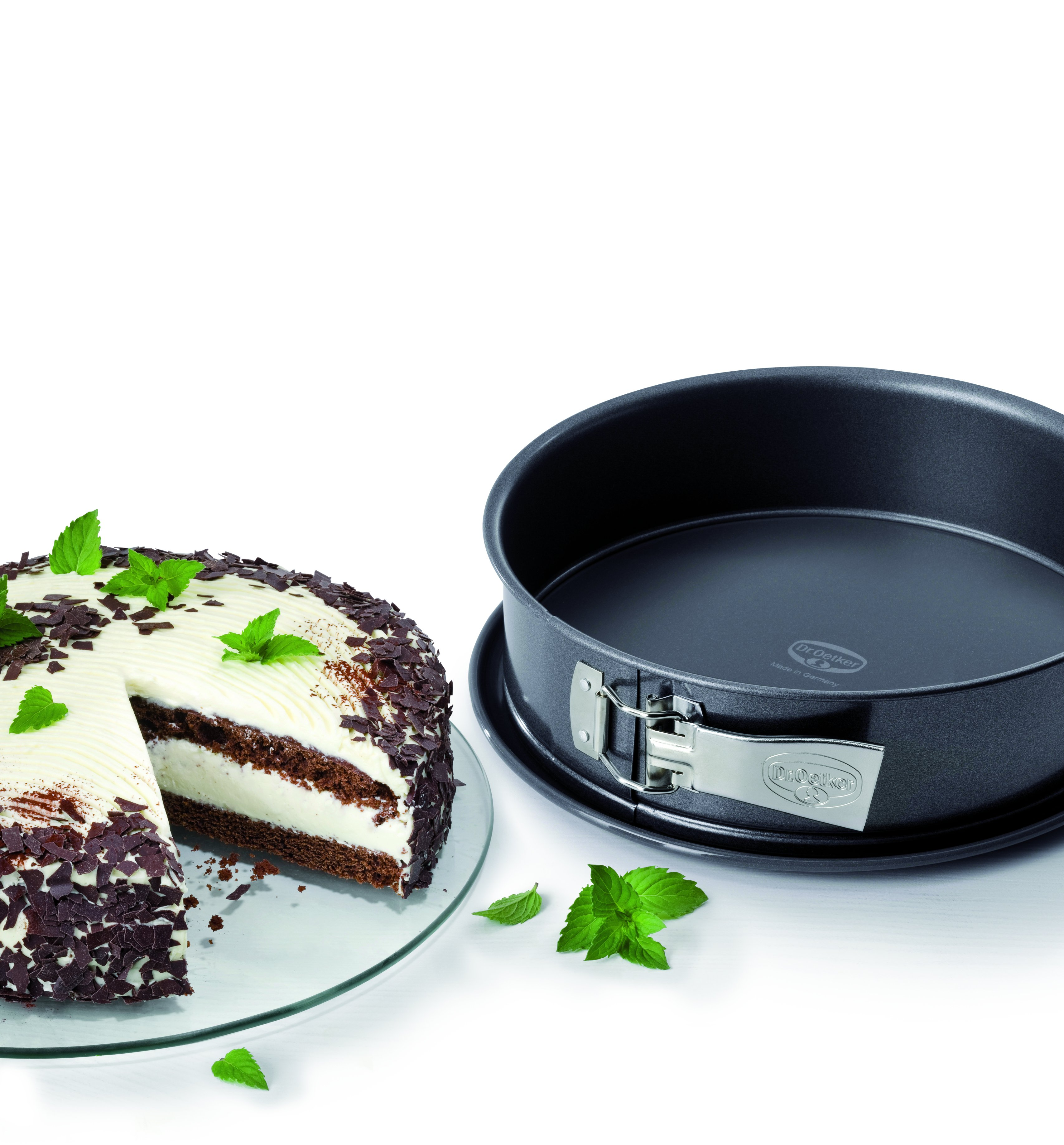 Ein Kuchenstück auf einem Teller neben einer Kuchenform und einem ganzen Kuchen.