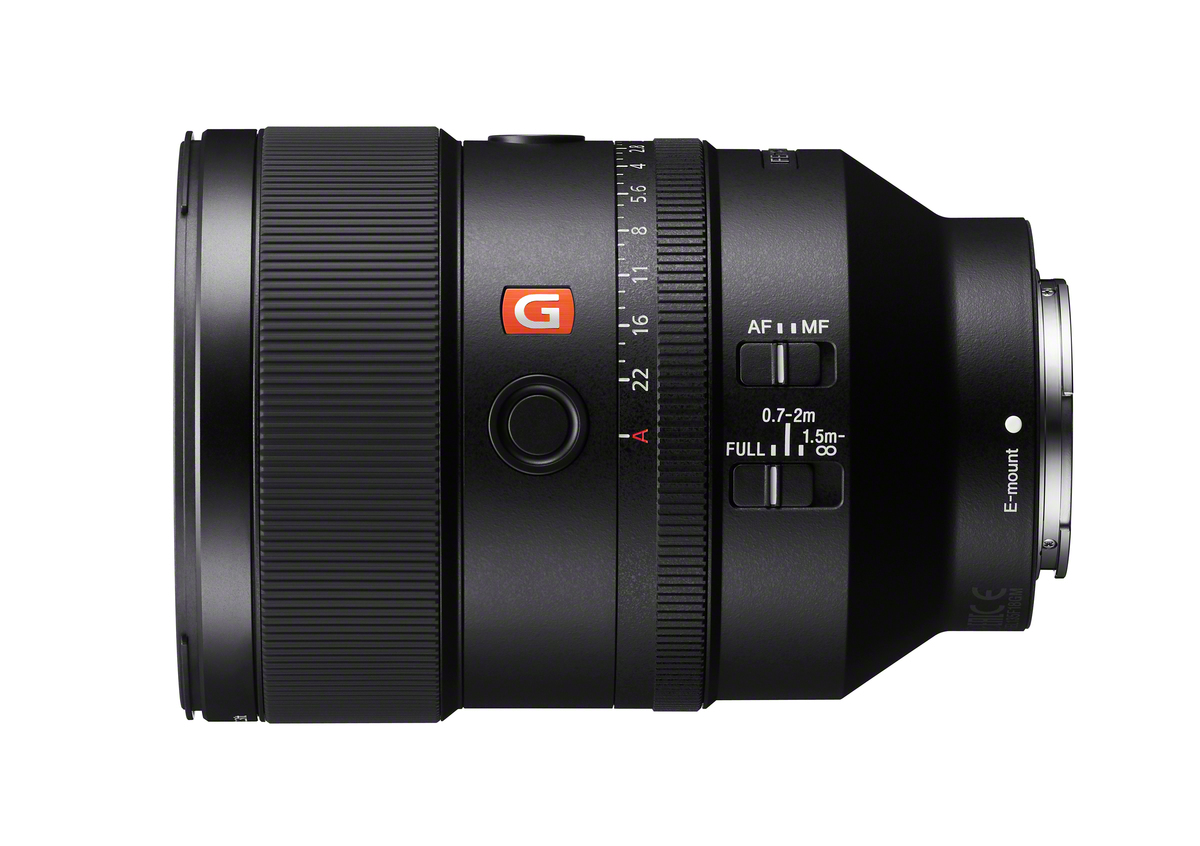 Un obiettivo per fotocamera Sony nero con segni bianchi, un logo 'G' rosso e vari anelli di regolazione, su sfondo bianco.