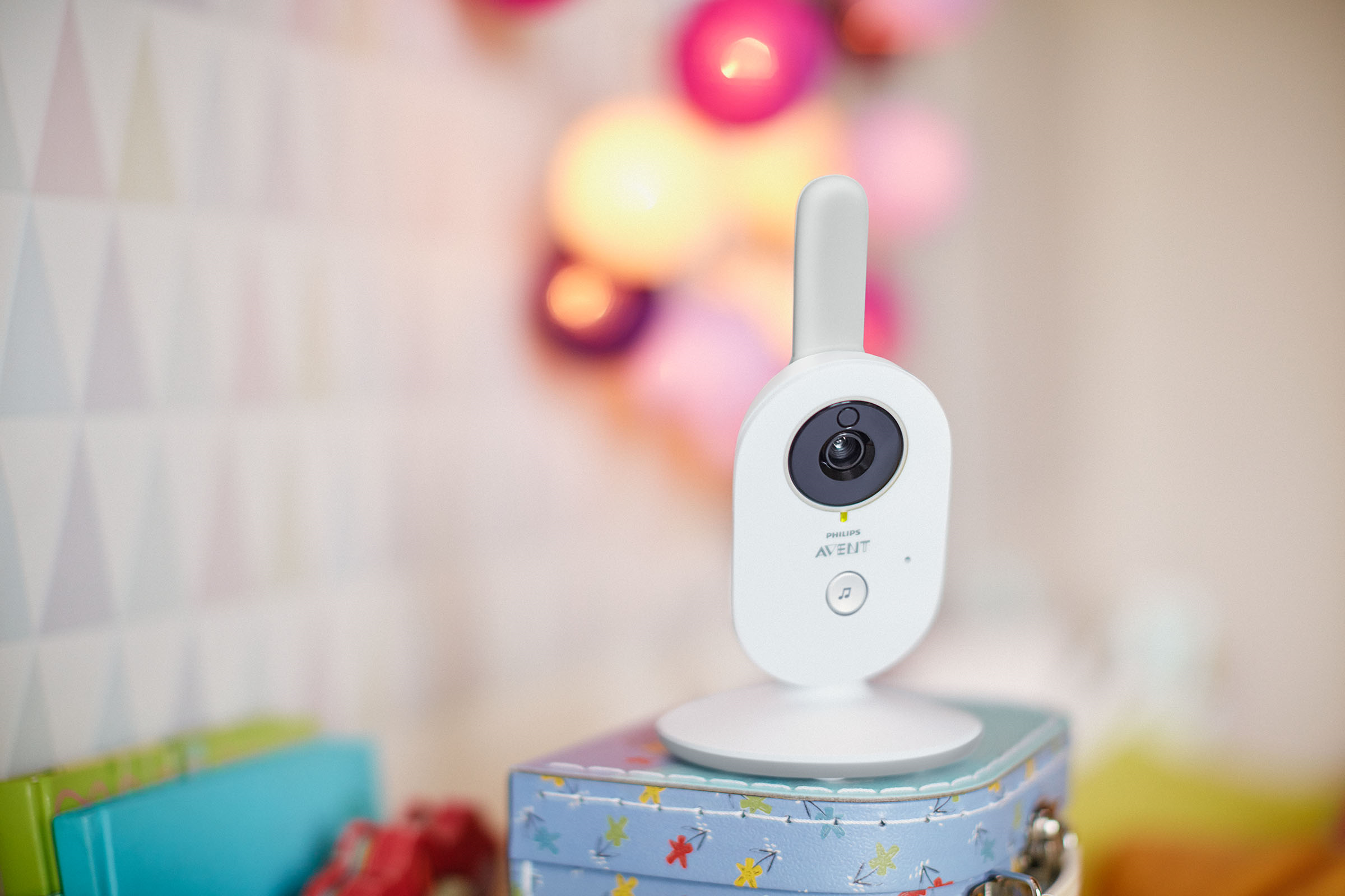 Weißer Babyphone auf blauer Box. Hintergrund hat verschwommene Lichter und gemusterte Wand.