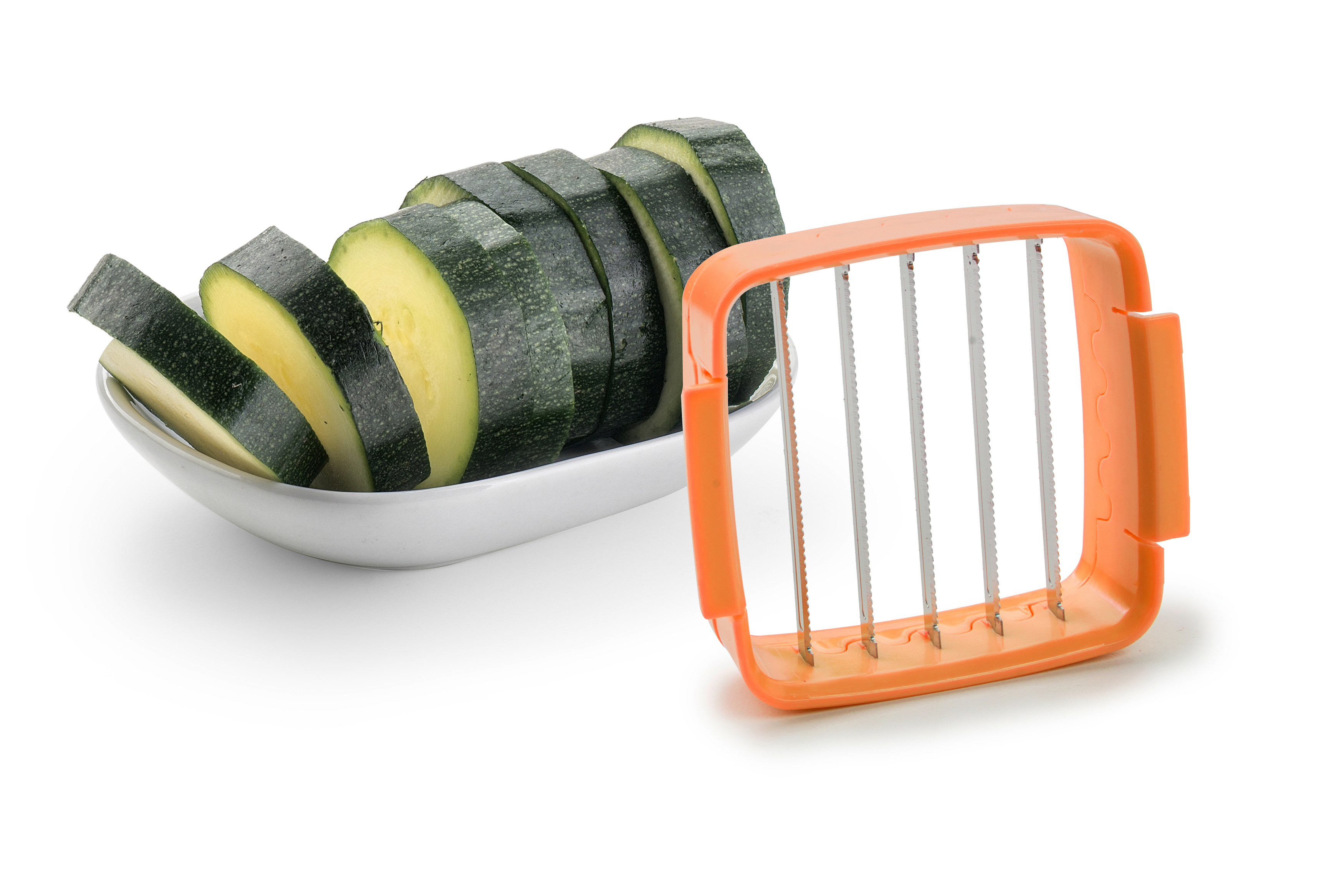 Geschnittene Zucchini auf einem weißen Teller und ein orangefarbener Gemüseschneider.