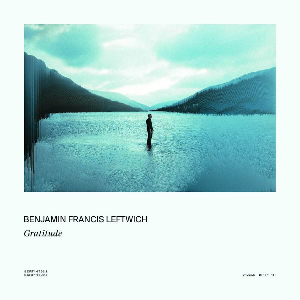 Homme debout dans l'eau, regardant les montagnes. Eau et ciel bleus. Pochette d'album.