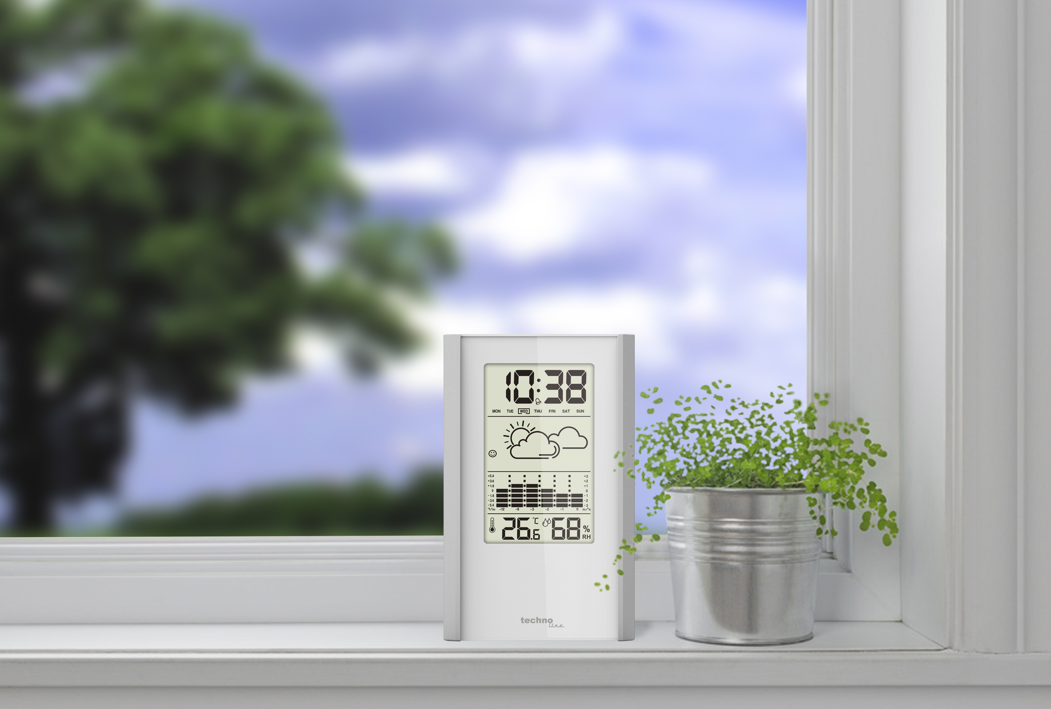 Wetterstation auf Fensterbank, mit Blick auf einen Baum.