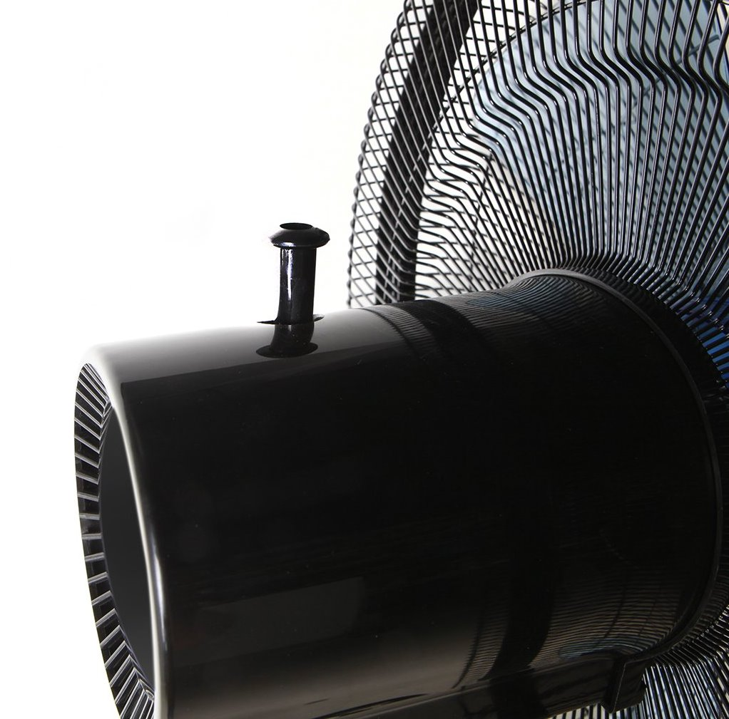 Primer plano de la carcasa negra de un ventilador con rejilla. Una pequeña perilla negra sobresale de la parte superior.