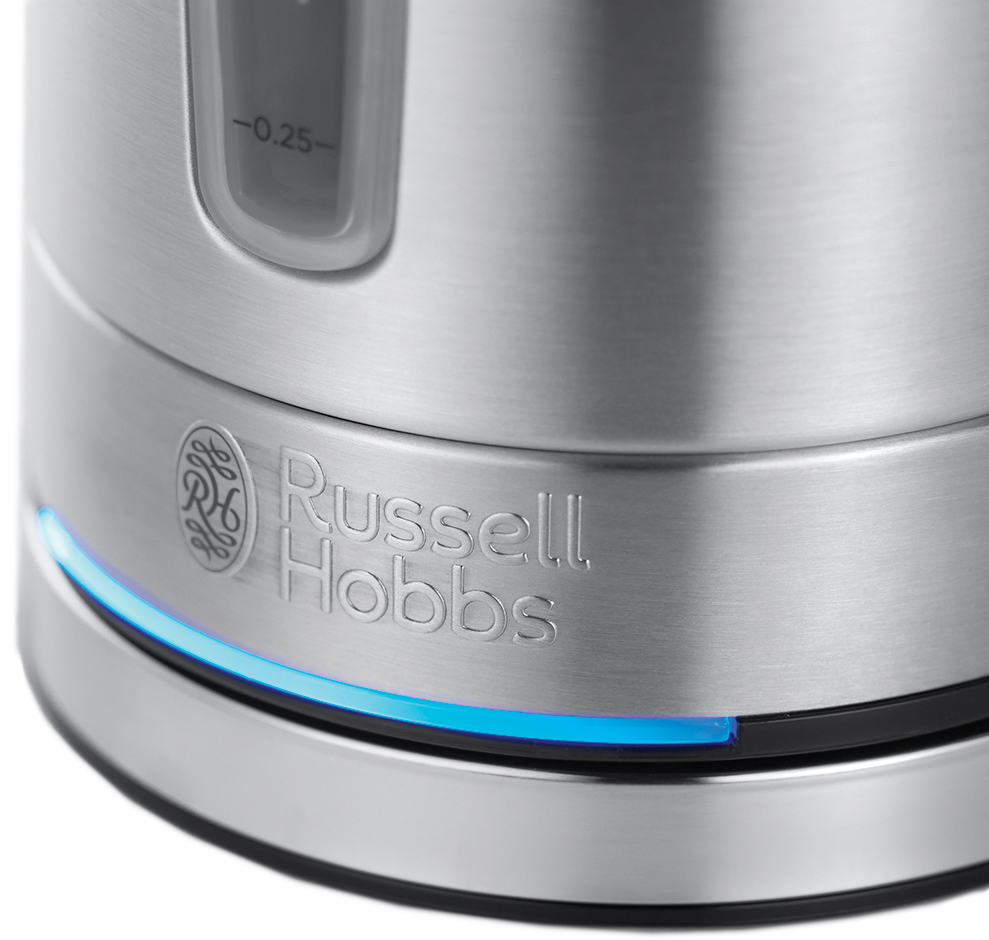 Közelkép egy ezüst Russell Hobbs vízforralóról, melynek talpát kék fény világítja.