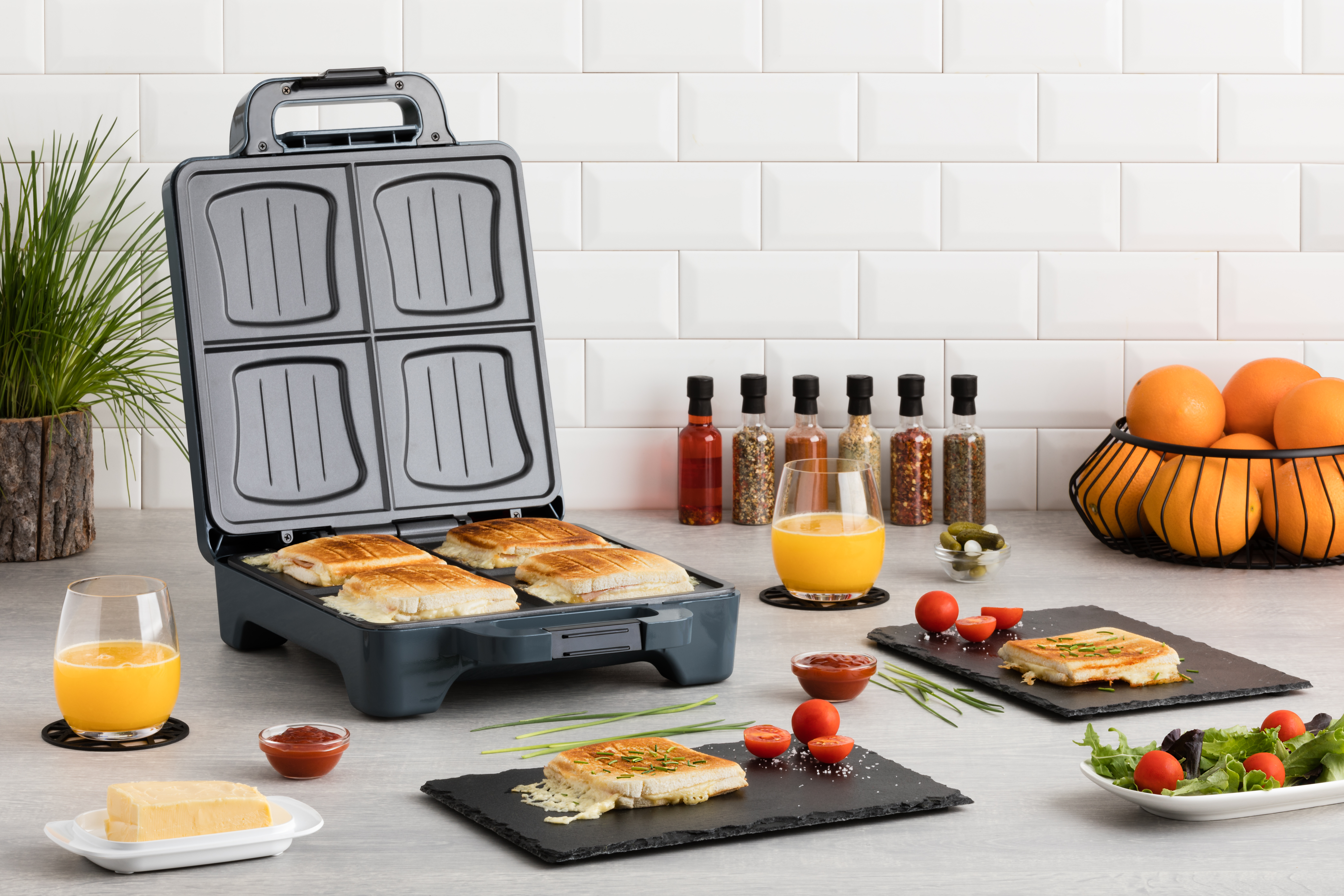 Appareil à sandwichs avec quatre sandwichs. Une personne prépare une assiette de nourriture.