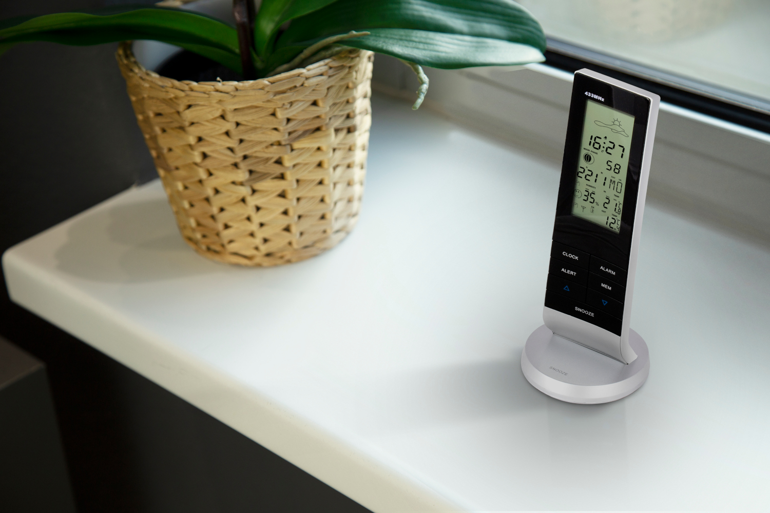 Digital clock displaying time and weather information on a white windowsill.