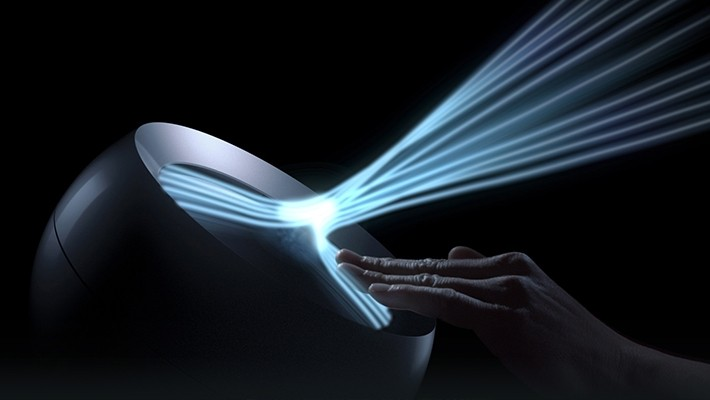 Hand interagiert mit Gerät. Blaue Lichtstrahlen gehen vom Gerät zur Hand aus.