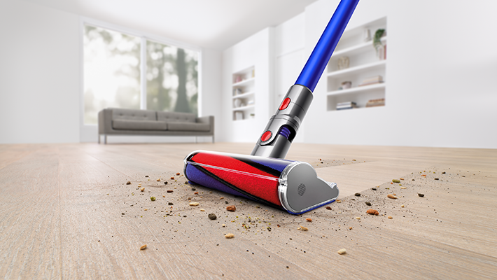 Ein Staubsauger reinigt den Boden und entfernt Schmutz und Ablagerungen von einem Holzboden.