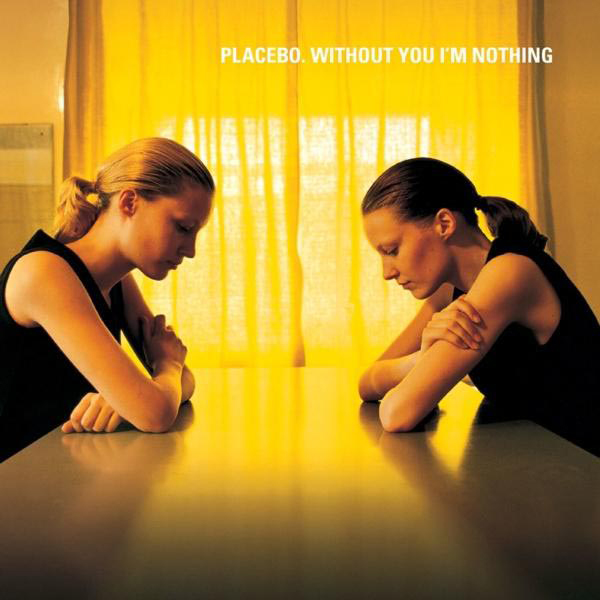 Albumcover mit zwei Frauen, die auf einen Tisch vor einer gelben Wand blicken.