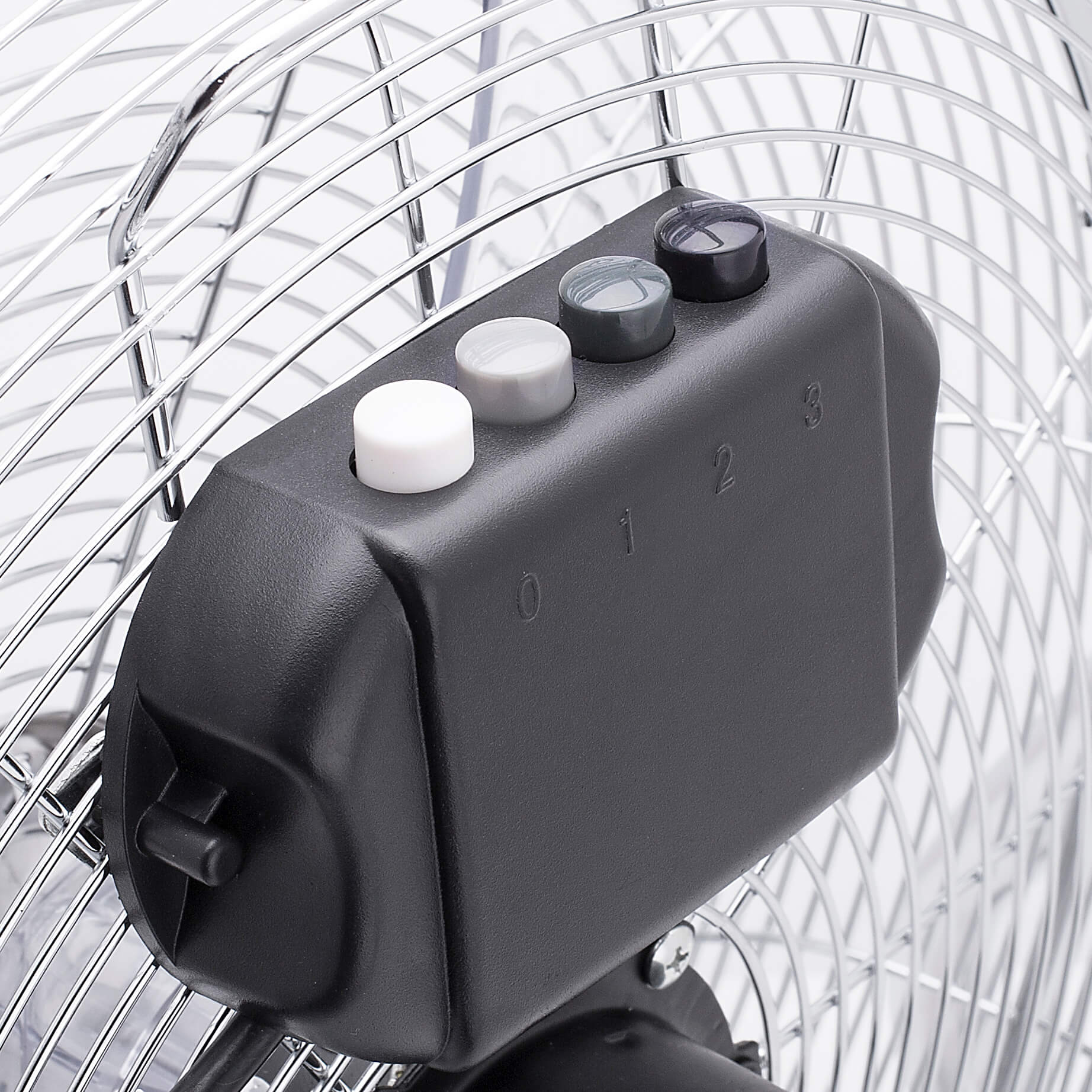 Close-up van een ventilatorbedieningspaneel met knoppen. De ventilator heeft een metalen kooi. Knoppen zijn wit, grijs en zwart.