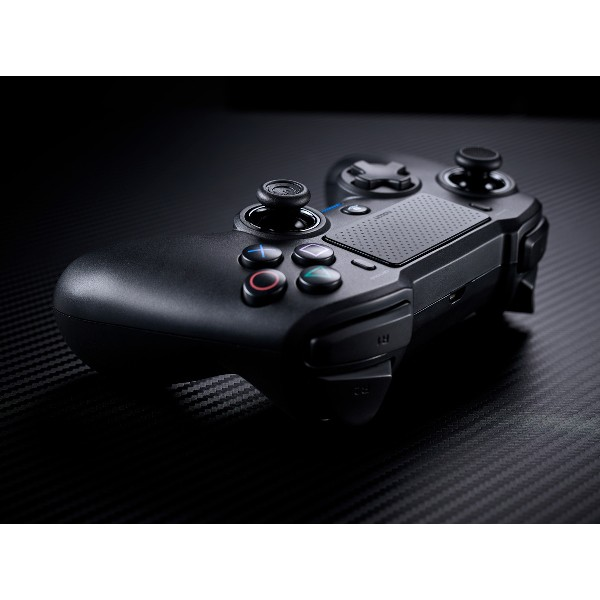 Mando de juegos negro sobre una superficie oscura texturizada, con botones, joysticks y touchpad central.