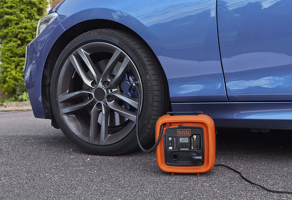 Egy narancssárga Black and Decker gumiabroncs-felfújó kék autógumihoz csatlakoztatva.