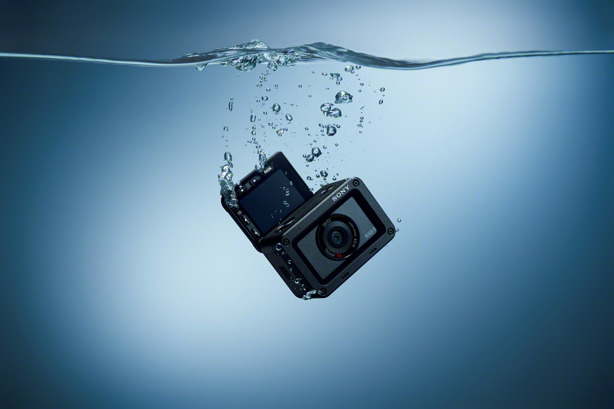 Schwarze Action-Kamera, die in blauem Wasser versinkt. Blasen und Wasseroberfläche sind sichtbar.